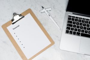 Auf dem Bild ist ein Blatt Papier auf dem Tutorial steht so wie ein Laptop zu sehen. Samir Jajjawi stellt 11 Regeln für den Erfolg von Change Prozessen vor.